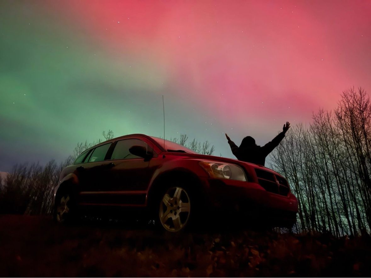 Arms up behind the Caliber under the aurora