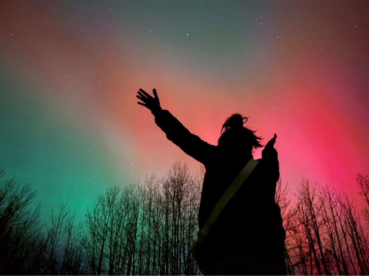 Silhouette with an arm raised to the aurora