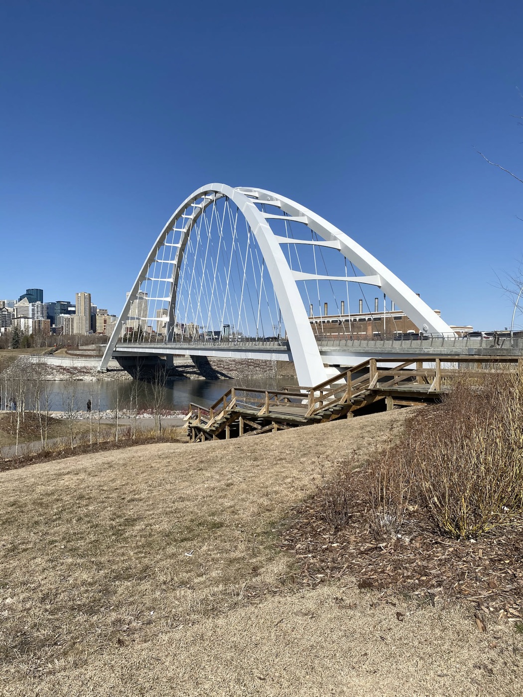 The white arch of the Walterdale Bridge over the river valley, downtown Edmonton behind it